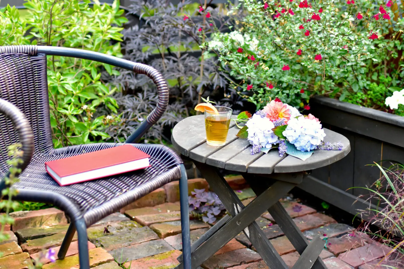Garden chair and table with book, flowers.